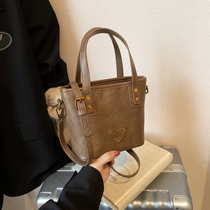 Deep brown faux leather tote bag with metallic logo and adjustable crossbody strap
