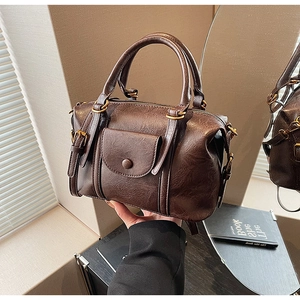 Close-up of vintage dark brown leather boston bag with golden metal hardware and flap pocket