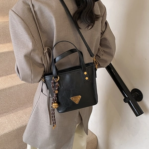 Fashionable black bucket bag with gold hardware and shoulder strap shown in a lifestyle view