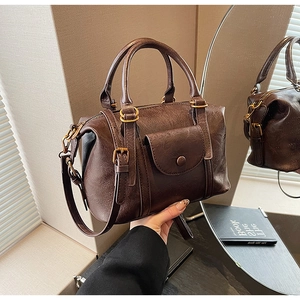 Close-up of vintage dark brown Boston bag with aged leather texture and brass hardware