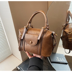 Detailed view of a vintage brown handbag with metal buckle and soft PU leather texture