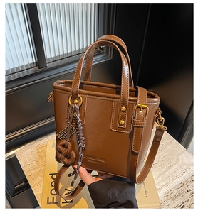 Detailed shot of brown vintage bucket bag featuring gold hardware and a pretzel charm