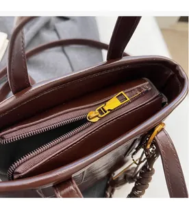 Close-up of smooth gold zipper and dark brown leather texture on a tote bag