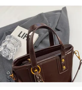Detailed close-up of brown faux leather handbag with golden hardware and twin handles