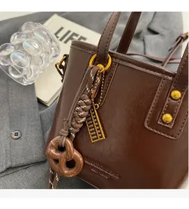 Close-up of dark brown vintage leather tote bag with unique abacus and woven charms