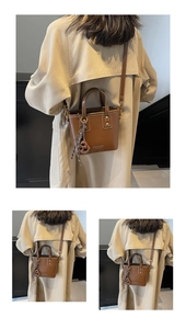 Detail view of brown leather bucket bag with top handle and woven ball charm decoration