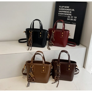 Chic bucket bags in black, red, and brown on a minimalist display stand with premium finish