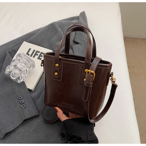 Detail of vintage brown bucket bag with embossed logo and premium gold metal rivets