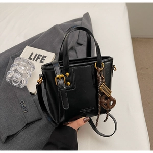 Detail of black bucket bag with vintage gold hardware and a unique abacus charm