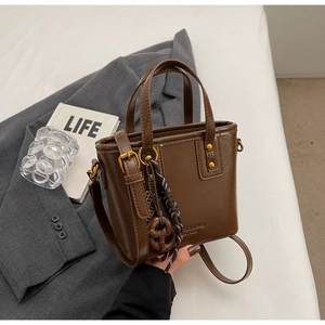 Close-up of vintage brown leather bucket bag with brand logo and woven charm detail