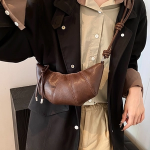 Retro dark brown croissant crossbody bag in glossy faux leather worn by a model