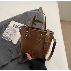 Detailed view of vintage brown bucket bag with gold rivets and MIAXIANGBAG logo