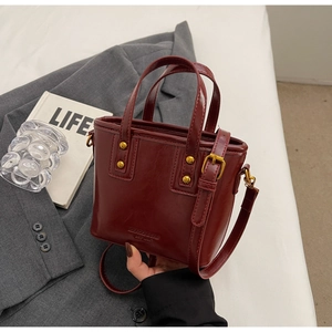 Close-up of wine red retro bucket bag with gold hardware and embossed branding detail