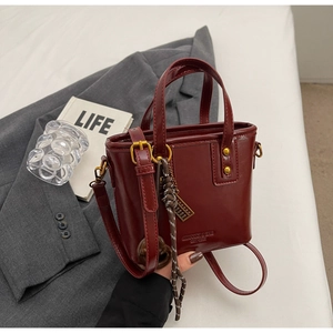 Detail view of burgundy leather bucket bag with gold hardware and woven rope accessory