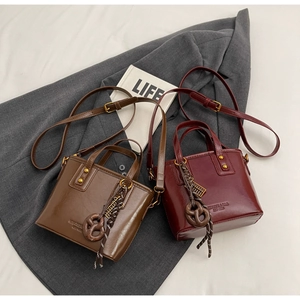 Flat lay detail of vintage leather bucket bags in deep brown and burgundy with gold hardware