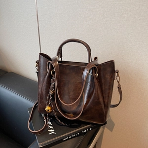 Vintage dark brown tote bag with woven bell charm and adjustable shoulder strap