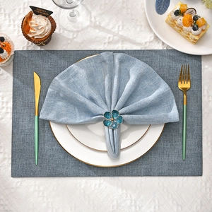 Close-up of blue floral napkin ring with gold trim on elegant table setting scene