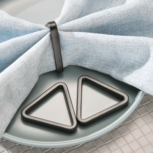 Modern matte black triangle and geometric napkin rings on a blue linen napkin