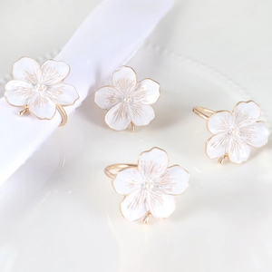 Detail of elegant white enamel plum blossom napkin rings with pearls on table cloth