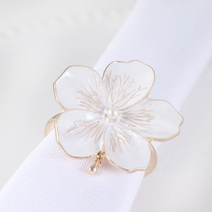 Macro shot of white enamel flower napkin ring with pearl center on golden metal band