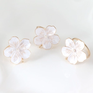 Detailed view of white enamel cherry blossom napkin rings with gold trim and central pearls