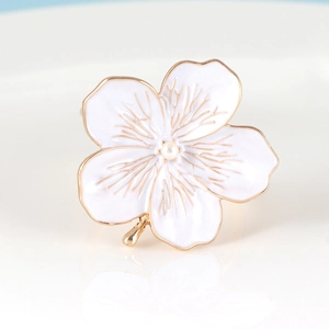 Macro detail of plum blossom napkin ring with white enamel petals and gold veins