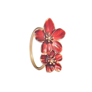 Vista detallada de dos flores de esmalte rojo sobre un servilletero de metal dorado