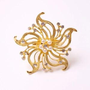 Macro detail of golden flower napkin ring with central pearls and sparkling rhinestones