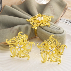 Set of three gold flower napkin rings with elegant white pearls and sparkling rhinestones