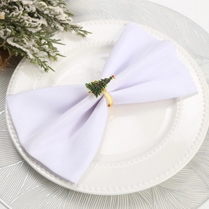 Golden Christmas tree napkin ring with green enamel on white napkin and ceramic plate