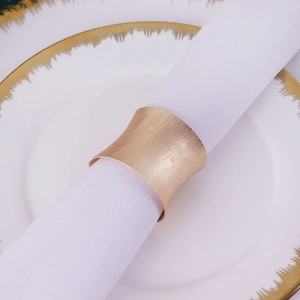 Macro shot of matte gold napkin ring with vertical texture on a white cloth and plate