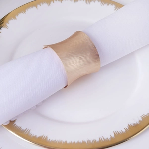 Elegant matte gold napkin ring with vertical texture on white porcelain plate