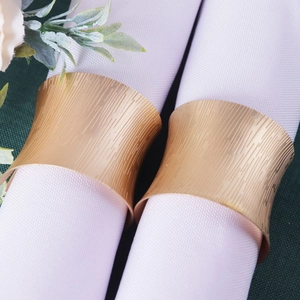 Matte gold napkin rings with vertical stripe texture and elegant waist-drum shape for dining