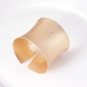 Macro shot of matte gold napkin ring with vertical ribbed texture for elegant table settings
