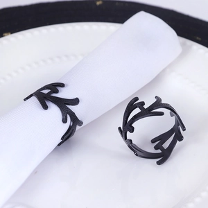 Nordic black resin napkin rings featuring a minimalist coral branch design on white plates