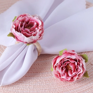 Close-up of pink artificial rose napkin ring with faux dew drops and woven base