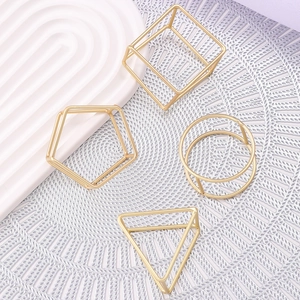 Set of four geometric gold metal napkin rings in triangle, square, pentagon and circle shapes