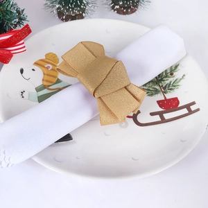 Golden woven fabric bow napkin ring on a festive Christmas themed dinner plate