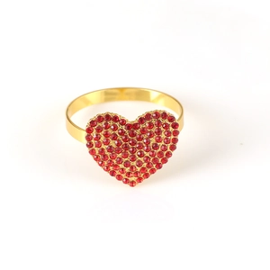 Close-up of heart-shaped napkin ring with red rhinestones on a gold metal base