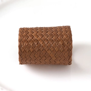Gros plan détaillé du rond de serviette en cuir PU tressé marron à motif croisé texturé
