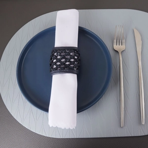 Détail du rond de serviette tressé en cuir PU bleu marine sur table dressée