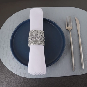 Vue détaillée du rond de serviette tressé argenté sur une décoration de table
