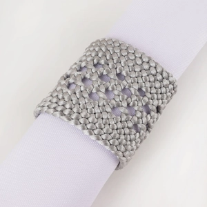 Rond de serviette en cuir PU tressé gris argenté vu à 45 degrés sur un tissu blanc
