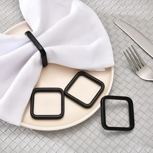 Set of 4 matte black square napkin rings with rounded edges on a modern table setting