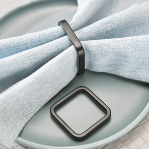 Modern matte black square napkin ring set on a plate with blue cloth napkin