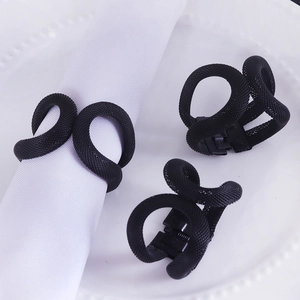 Close-up of black woven mesh napkin rings with spring clips on elegant white dinnerware