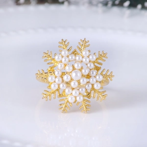 Elegant gold snowflake napkin ring with white pearls on a textured background