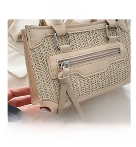 Detalle del bolso de hombro tejido blanco roto con adornos de cuero y cremalleras