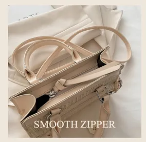 Detalle de la textura tejida beige y asa de cuero con cremallera metálica en bolso