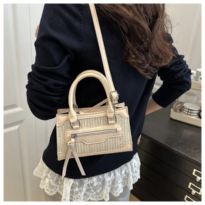 Detalle del bolso bandolera tejido crema con diseño de paja y correa de cuero